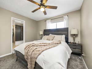 Bedroom featuring ceiling fan, a textured ceiling, and dark colored carpet