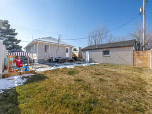 Rear view of property with a yard, a playground, and a jacuzzi