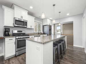 Kitchen featuring white cabinetry, stainless steel appliances, and a center island