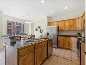 Kitchen featuring pendant lighting, sink, a kitchen island with sink, light tile patterned floors, and stainless steel appliances