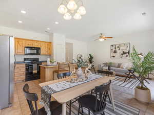 Dining space featuring ceiling fan with notable chandelier and light tile patterned floors