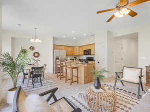 Living room featuring ceiling fan with notable chandelier and light tile patterned floors