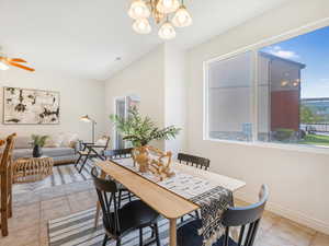 Dining area with light tile patterned floors and ceiling fan with notable chandelier