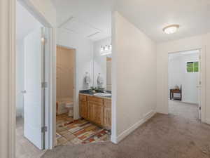 Corridor featuring sink and light carpet