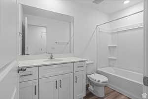 Full bathroom with hardwood / wood-style flooring, vanity, bathtub / shower combination, and toilet