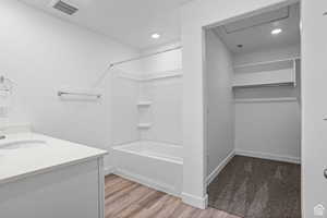 Bathroom with vanity, hardwood / wood-style flooring, and bathtub / shower combination