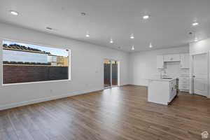 Kitchen with light wood-type flooring, sink, a center island with sink, and white cabinets