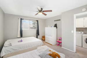 Bedroom featuring ceiling fan, light colored carpet, and washing machine and clothes dryer