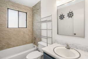 Full bathroom featuring vanity, tiled shower / bath, and toilet