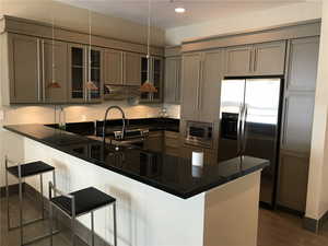 Kitchen with stainless steel appliances, kitchen peninsula, hanging light fixtures, and a breakfast bar area