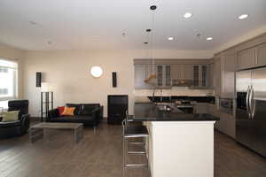 Kitchen featuring sink, gray cabinets, a breakfast bar, hanging light fixtures, and stainless steel appliances