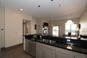 Kitchen with dishwasher, sink, dark tile patterned flooring, and decorative light fixtures