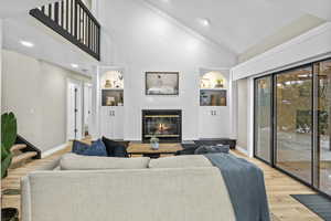 Living room featuring hardwood / wood-style flooring, high vaulted ceiling, and built in shelves