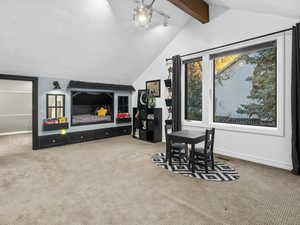 Interior space with vaulted ceiling with beams, a textured ceiling, and carpet