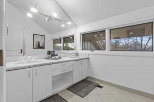 Bathroom with vanity, tile patterned flooring, and vaulted ceiling