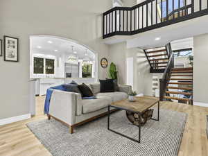 Living room with a towering ceiling, a chandelier, and light wood-type flooring