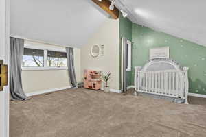 Unfurnished bedroom featuring lofted ceiling, light colored carpet, and rail lighting