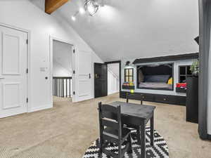 Carpeted dining area featuring lofted ceiling with beams and a textured ceiling