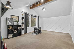 Playroom with light colored carpet, track lighting, and vaulted ceiling with beams