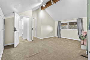 Bonus room with vaulted ceiling with beams, light colored carpet, and a textured ceiling