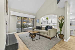 Living room with high vaulted ceiling and light hardwood / wood-style flooring