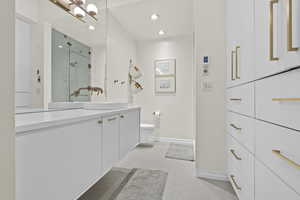 Bathroom with walk in shower, tile patterned floors, vanity, and toilet