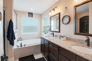 Bathroom featuring vanity, tiled tub, and tile patterned floors