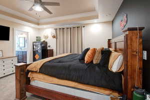 Bedroom with connected bathroom, ornamental molding, light colored carpet, and a raised ceiling