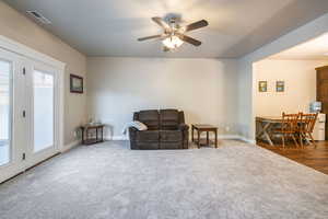 Living area featuring dark colored carpet and ceiling fan