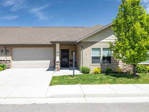 View of front of property with a garage, concrete driveway, stone siding, a shingled roof, and a front lawn