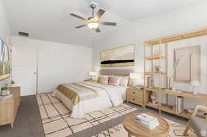 Carpeted bedroom with ceiling fan and lofted ceiling