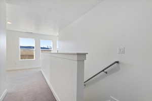 Hall with light colored carpet and a textured ceiling