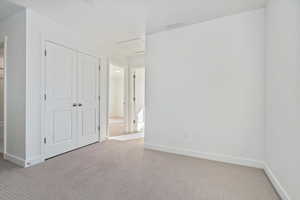 Unfurnished bedroom with light carpet and a closet