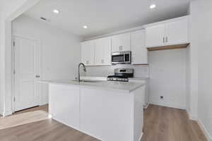 Kitchen with a kitchen island with sink, sink, white cabinetry, and stainless steel appliances