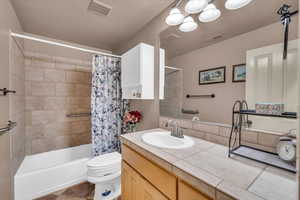 Full bathroom with vanity, shower / bath combination with curtain, and toilet