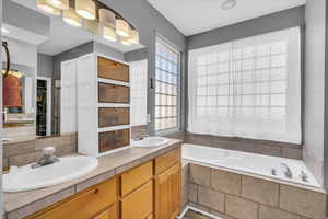 Bathroom with vanity, plenty of natural light, and tiled bath