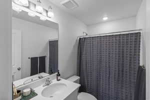 Bathroom featuring walk in shower, vanity, and toilet