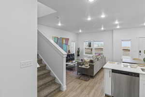 Kitchen featuring stainless steel dishwasher, white cabinets, and light hardwood / wood-style floors