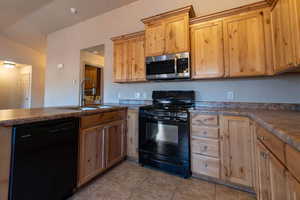 Kitchen with sink, black appliances, and light tile patterned flooring