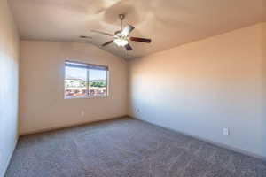 Empty room featuring a textured ceiling, vaulted ceiling, ceiling fan, and carpet