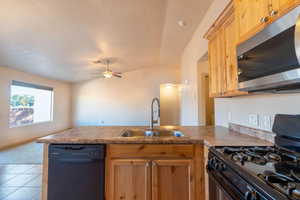 Kitchen with lofted ceiling, sink, kitchen peninsula, ceiling fan, and black appliances