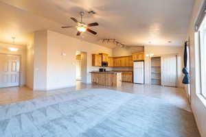 Kitchen with white refrigerator, light tile patterned flooring, hanging light fixtures, and vaulted ceiling