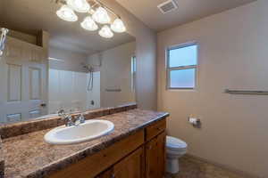 Bathroom featuring tile patterned flooring, vanity, toilet, a chandelier, and walk in shower