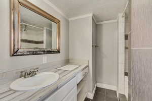 Bathroom featuring vanity, a shower, ornamental molding, and a textured ceiling