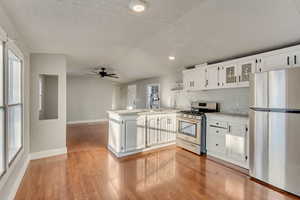 Kitchen featuring sink, stainless steel appliances, kitchen peninsula, and white cabinets