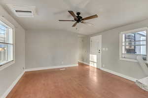 Unfurnished room featuring hardwood / wood-style floors, vaulted ceiling, a healthy amount of sunlight, and ceiling fan