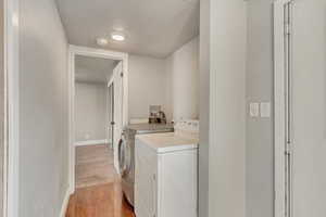 Laundry room with independent washer and dryer and light wood-type flooring