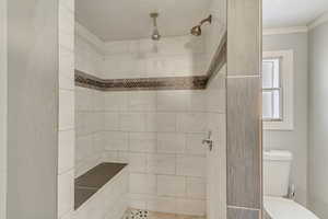 Bathroom with crown molding, tiled shower, and toilet