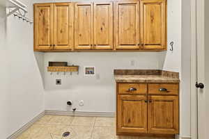 Laundry room with light tile patterned floors, hookup for a washing machine, cabinets, hookup for a gas dryer, and hookup for an electric dryer