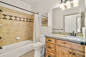 Full Guest bathroom featuring tile patterned flooring, vanity, toilet, and shower / tub combo with curtain